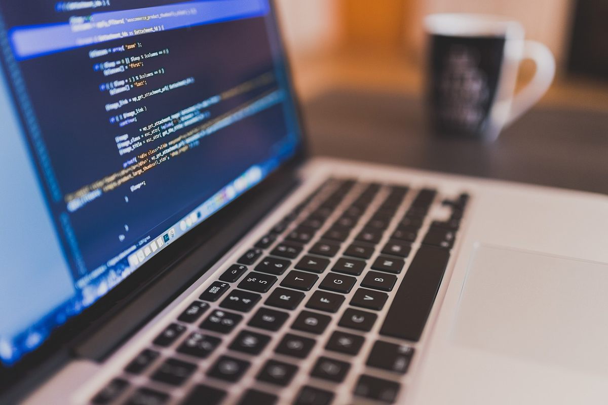 Photo montrant un ordinateur portable avec clavier et une tasse de café sur une table