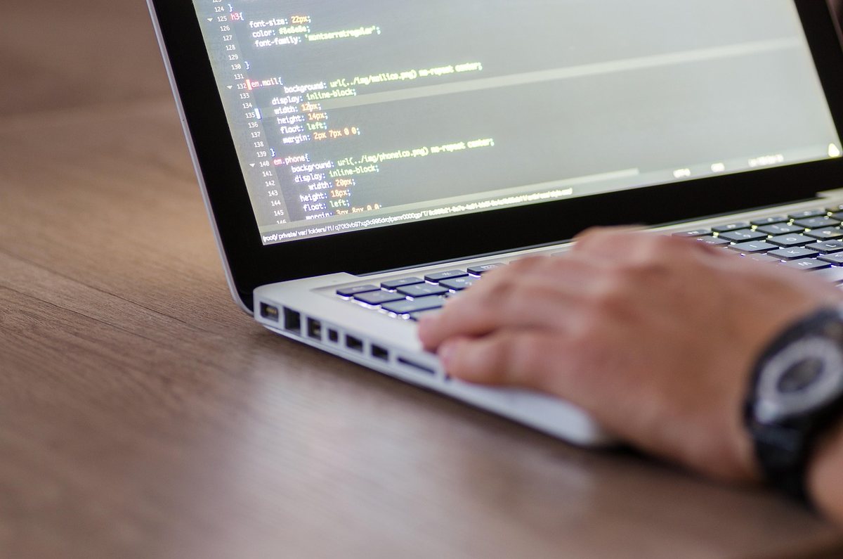 Une main tapotant le clavier d'un ordinateur portable sur une table en bois