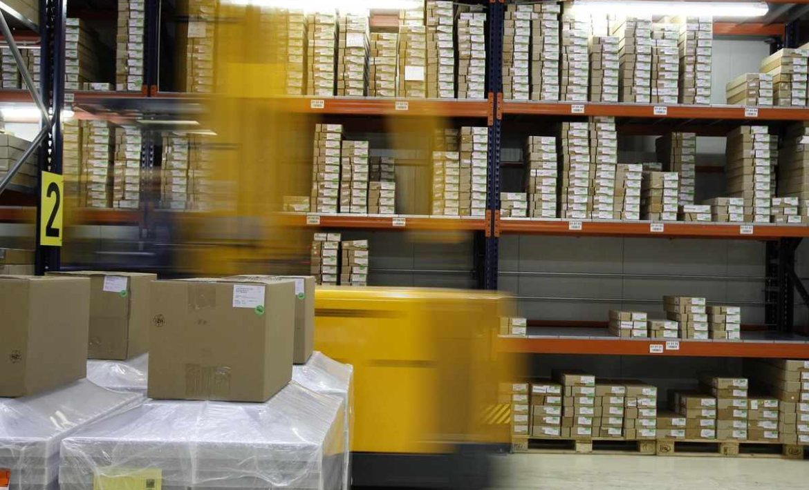 Un chariot élévateur déplace des palettes de cartons dans un entrepôt