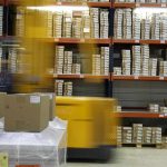 Un chariot élévateur déplace des palettes de cartons dans un entrepôt