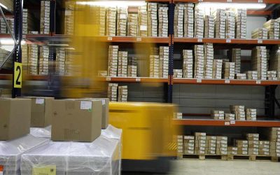 Un chariot élévateur déplace des palettes de cartons dans un entrepôt