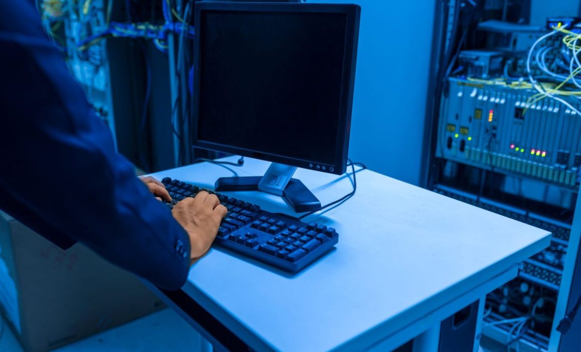 Une personne tapant sur un clavier devant un écran dans une salle de serveurs