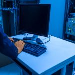 Une personne tapant sur un clavier devant un écran dans une salle de serveurs