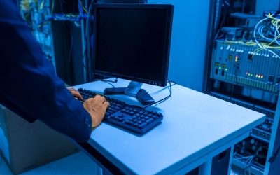 Une personne tapant sur un clavier devant un écran dans une salle de serveurs