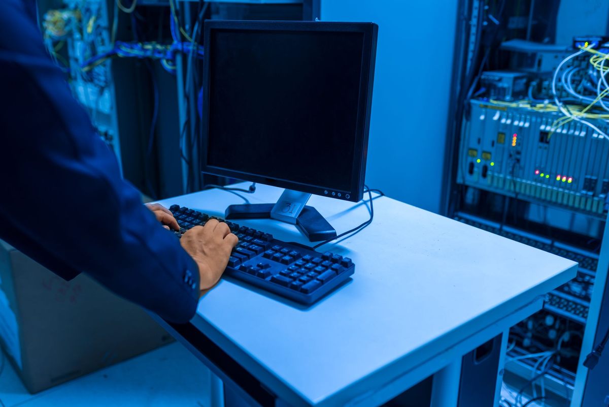Une personne tapant sur un clavier devant un écran dans une salle de serveurs