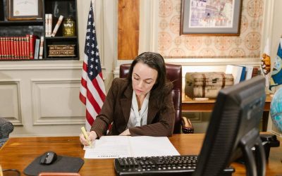 Femme écrivant à un bureau avec un drapeau américain, un clavier et un écran devant elle