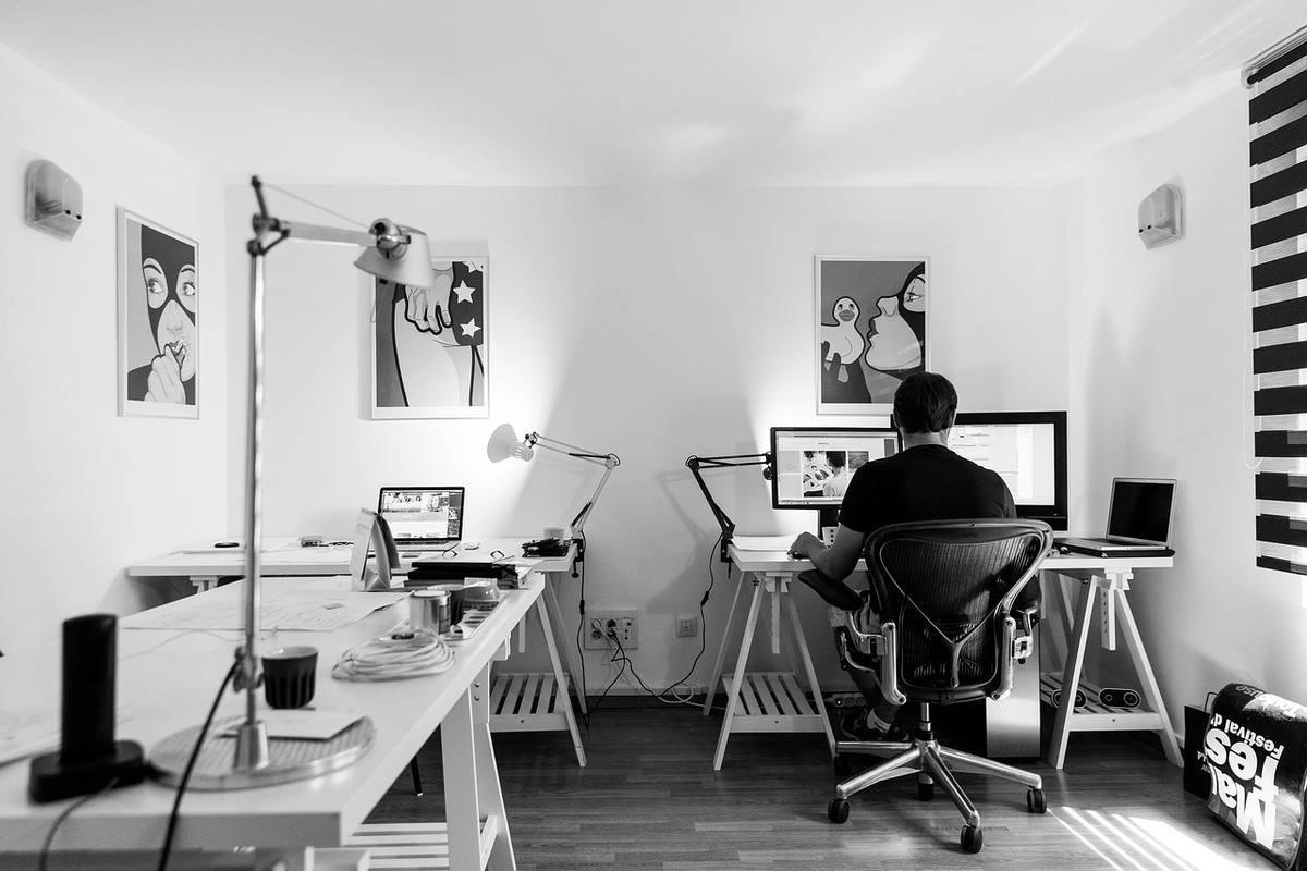 Un homme travaille sur ordinateur dans un bureau lumineux avec tableaux