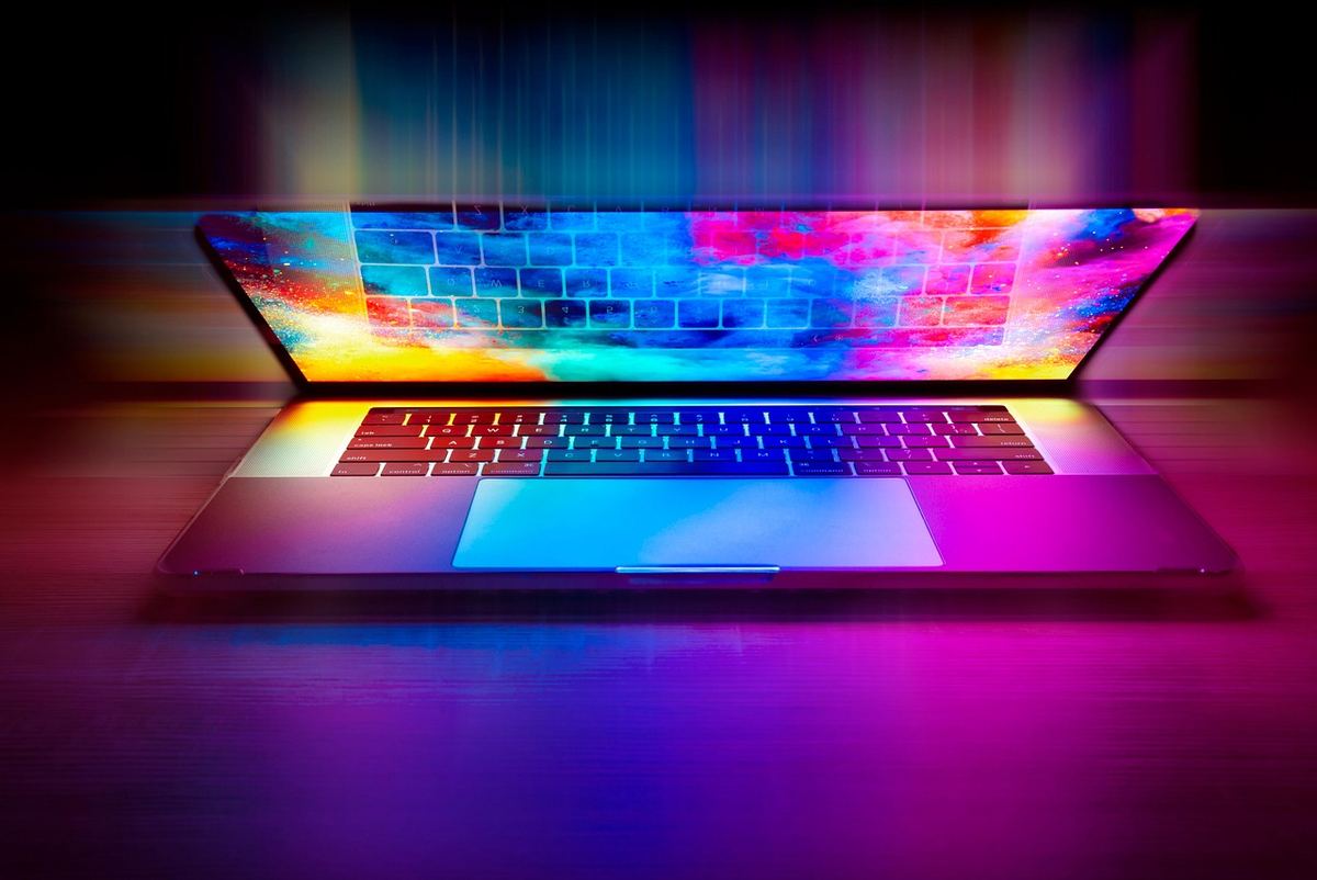Ordinateur portable allumé, écran et clavier éclairés, fond sombre