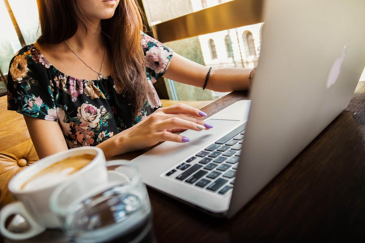 Une femme en chemise fleurie utilise un ordinateur portable à un bureau