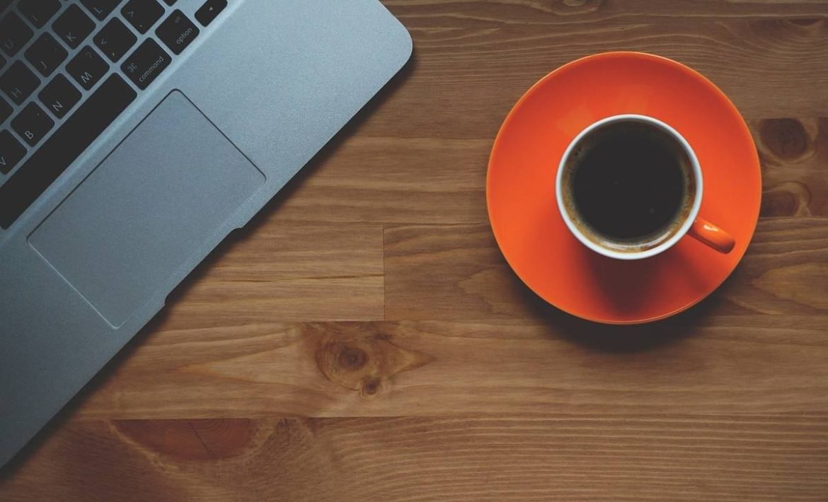 Un ordinateur portable et une tasse de café sur une assiette orange