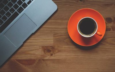 Un ordinateur portable et une tasse de café sur une assiette orange