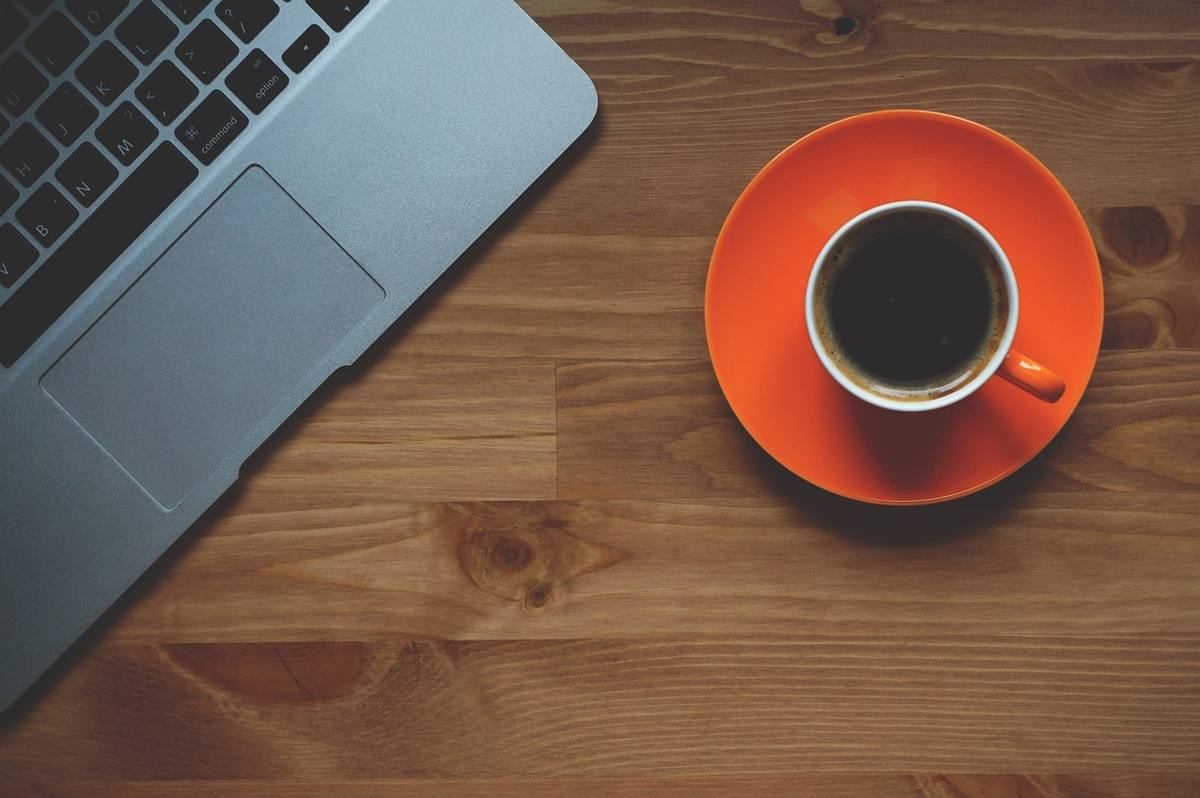 Un ordinateur portable et une tasse de café sur une assiette orange
