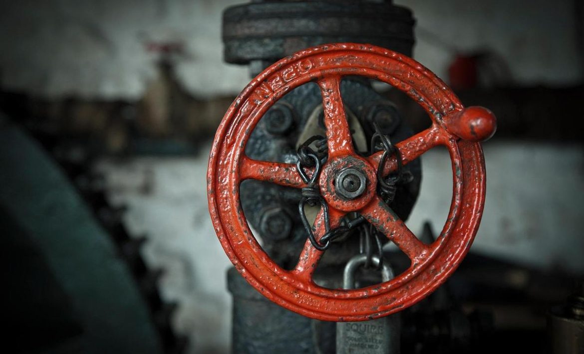 Grande roue rouge de vanne sur tuyau atelier sombre cadenas fixé