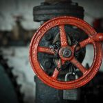 Grande roue rouge de vanne sur tuyau atelier sombre cadenas fixé