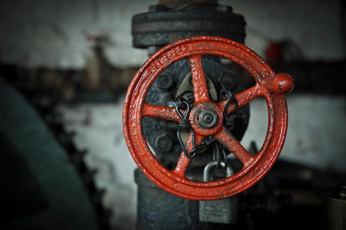 Grande roue rouge de vanne sur tuyau atelier sombre cadenas fixé